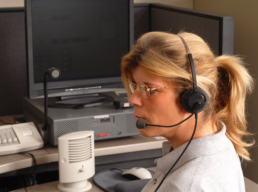 A female dispatcher in a grey shirt, focused and engaged in her work environment.