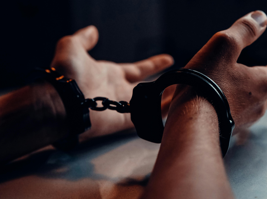 A close-up of a person's hands in handcuffs resting on a table