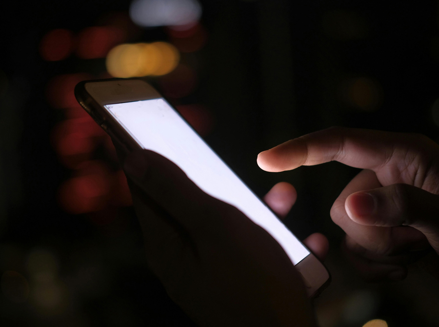 A hand holding a cell phone displaying a blank white screen