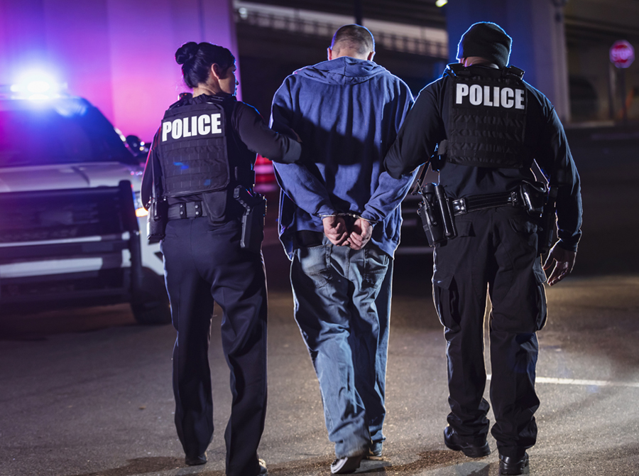 A man is under arrest, being escorted by two police officers, illustrating a serious police action.