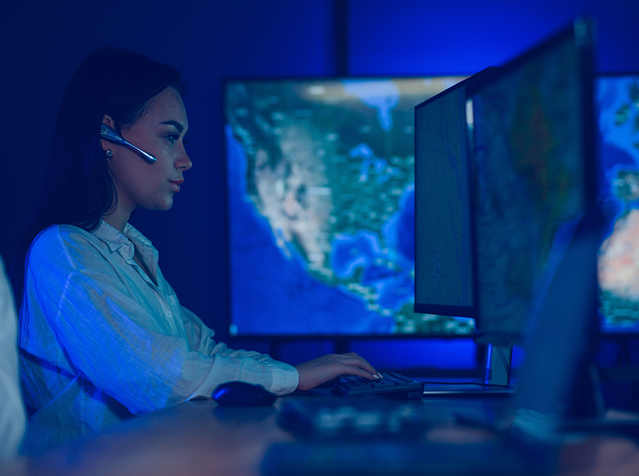 A woman in a headset diligently operates a computer, fulfilling her role as a dispatcher.