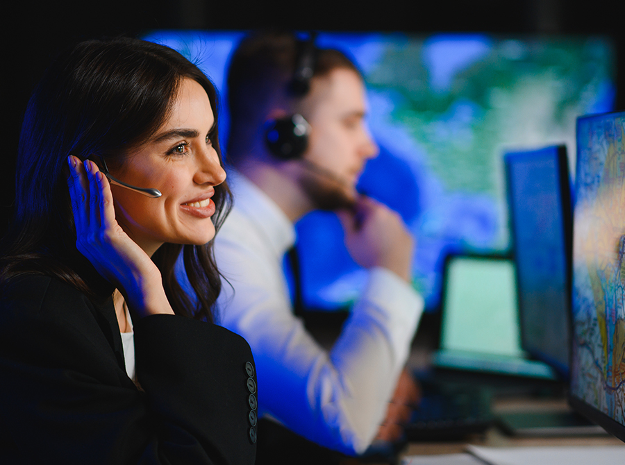 Female 9-1-1 dispatcher wearing a headset at a communications center, illustrating how to choose the right online dispatcher training for your communications center while managing emergency calls.