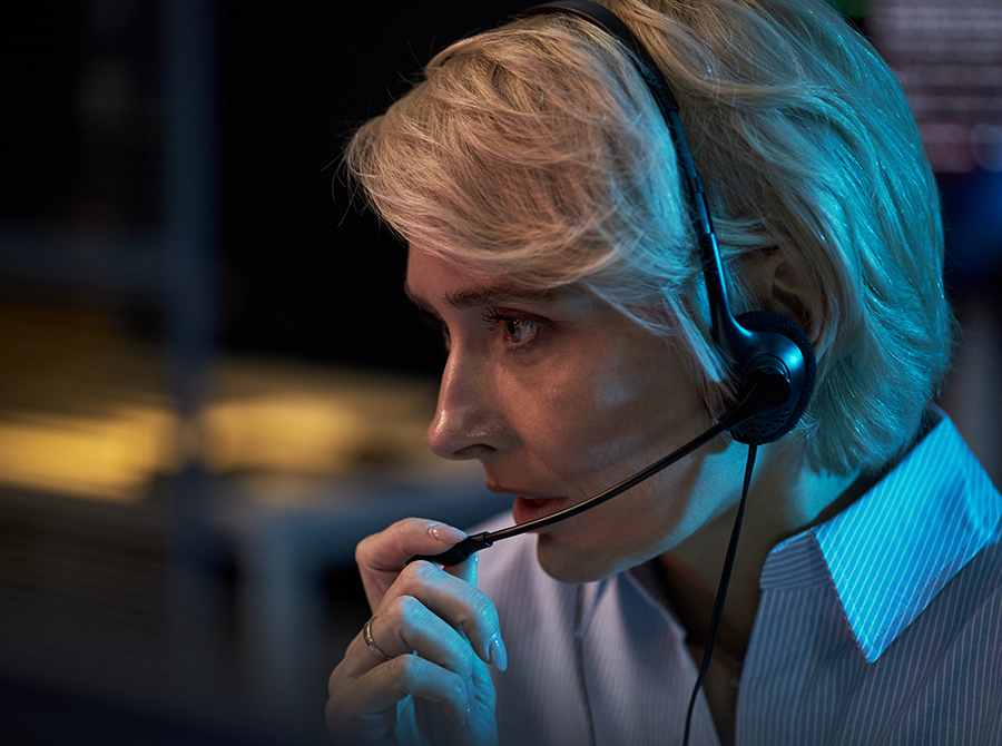 Female 9-1-1 dispatcher wearing a headset and handling emergency calls as part of PLS Dispatch Pro training.